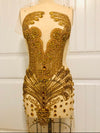 Gold beaded dress on a mannequin against a white paneled wall