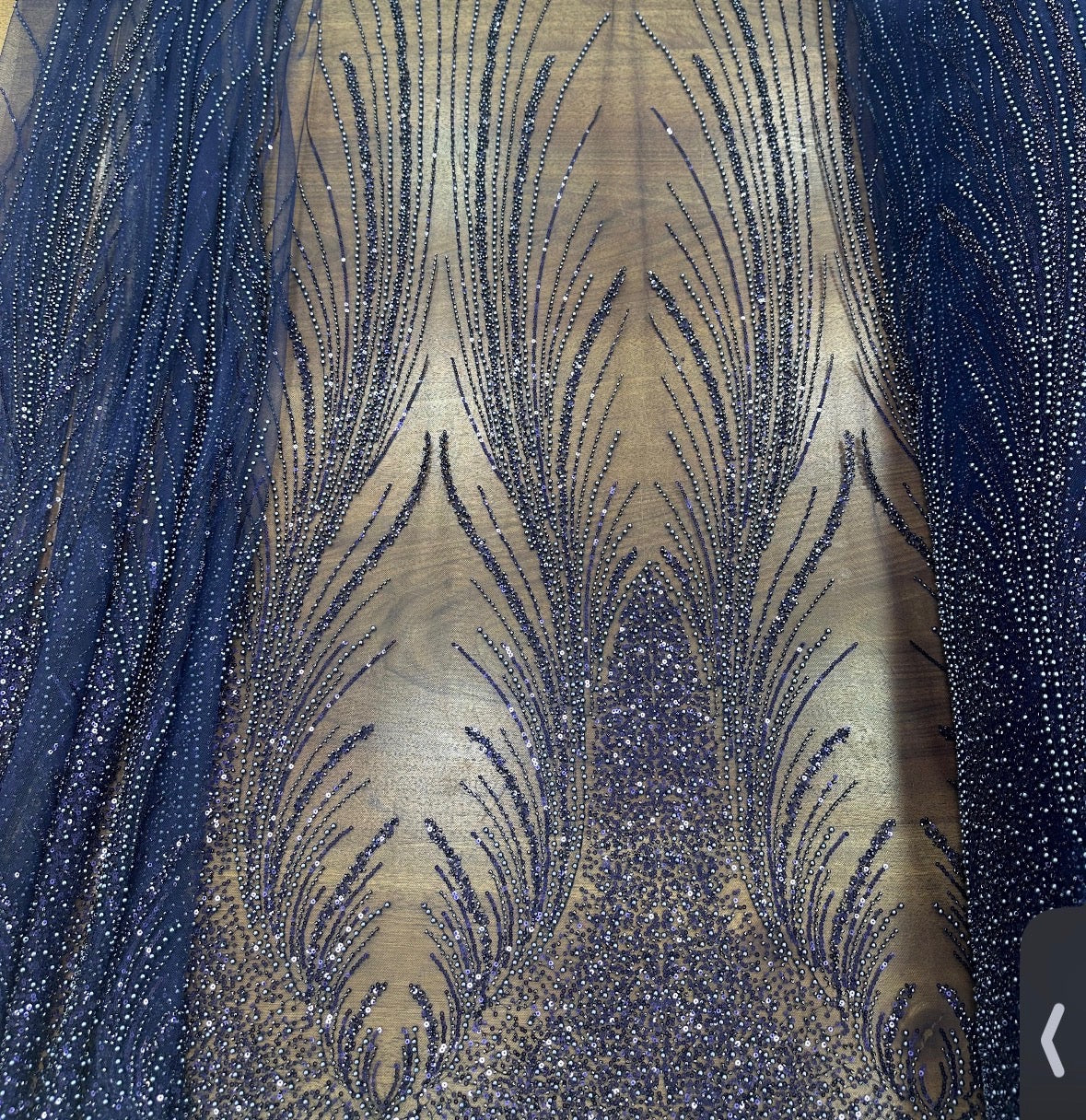Close-up of Angel Gown fabric swatch in navy blue and gold, beaded feather pattern colorway option