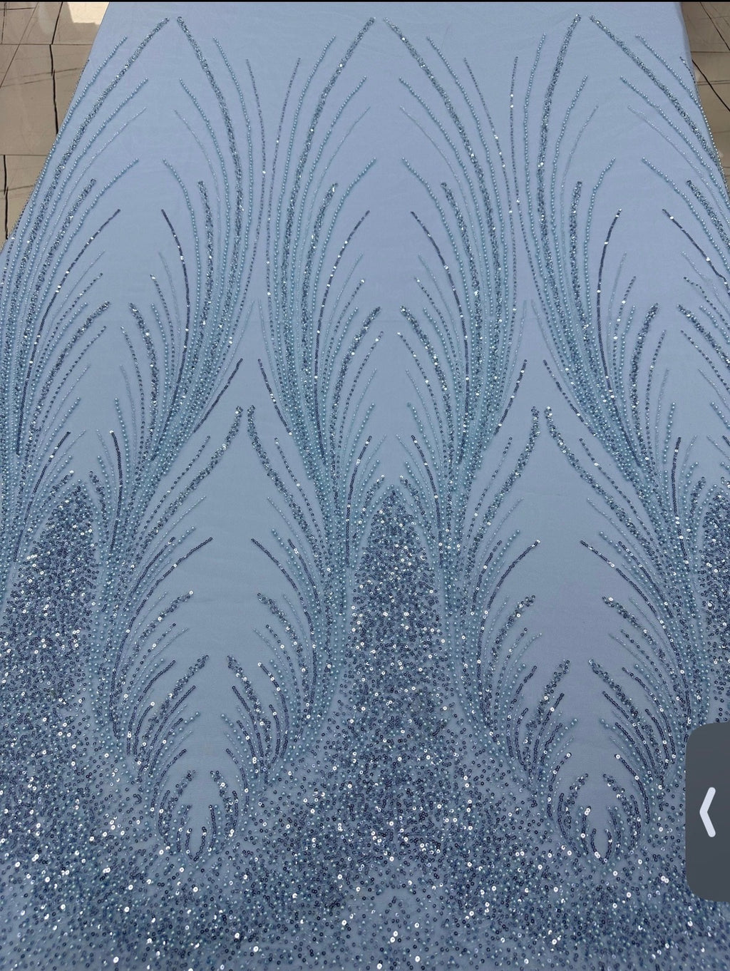 Close-up of Angel Gown fabric swatch, powder blue beaded feather pattern with crystal embellishment