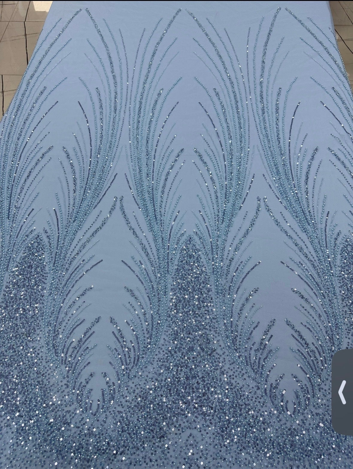 Close-up of Angel Gown fabric swatch, powder blue beaded feather pattern with crystal embellishment
