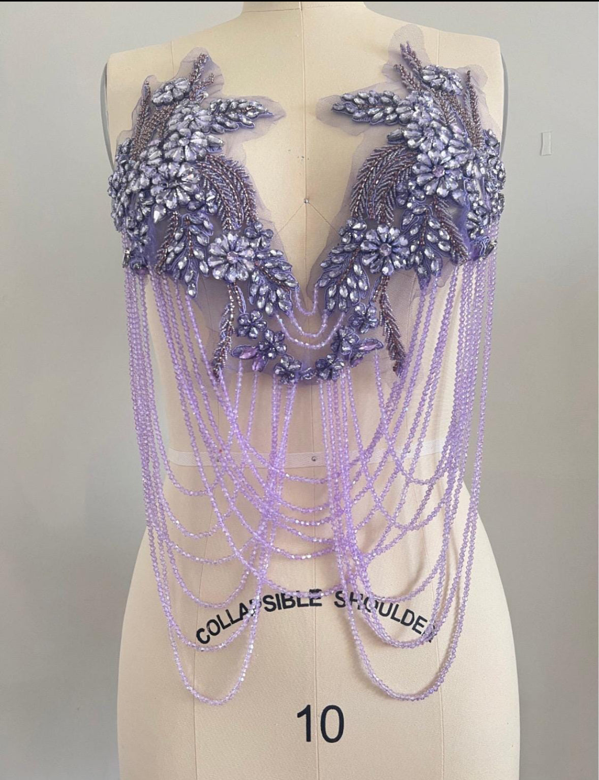 light purple applique beaded and chain shoulder piece on a mannequin with 'Collapsible Shoulder' label. Bellz Couture Detroit 