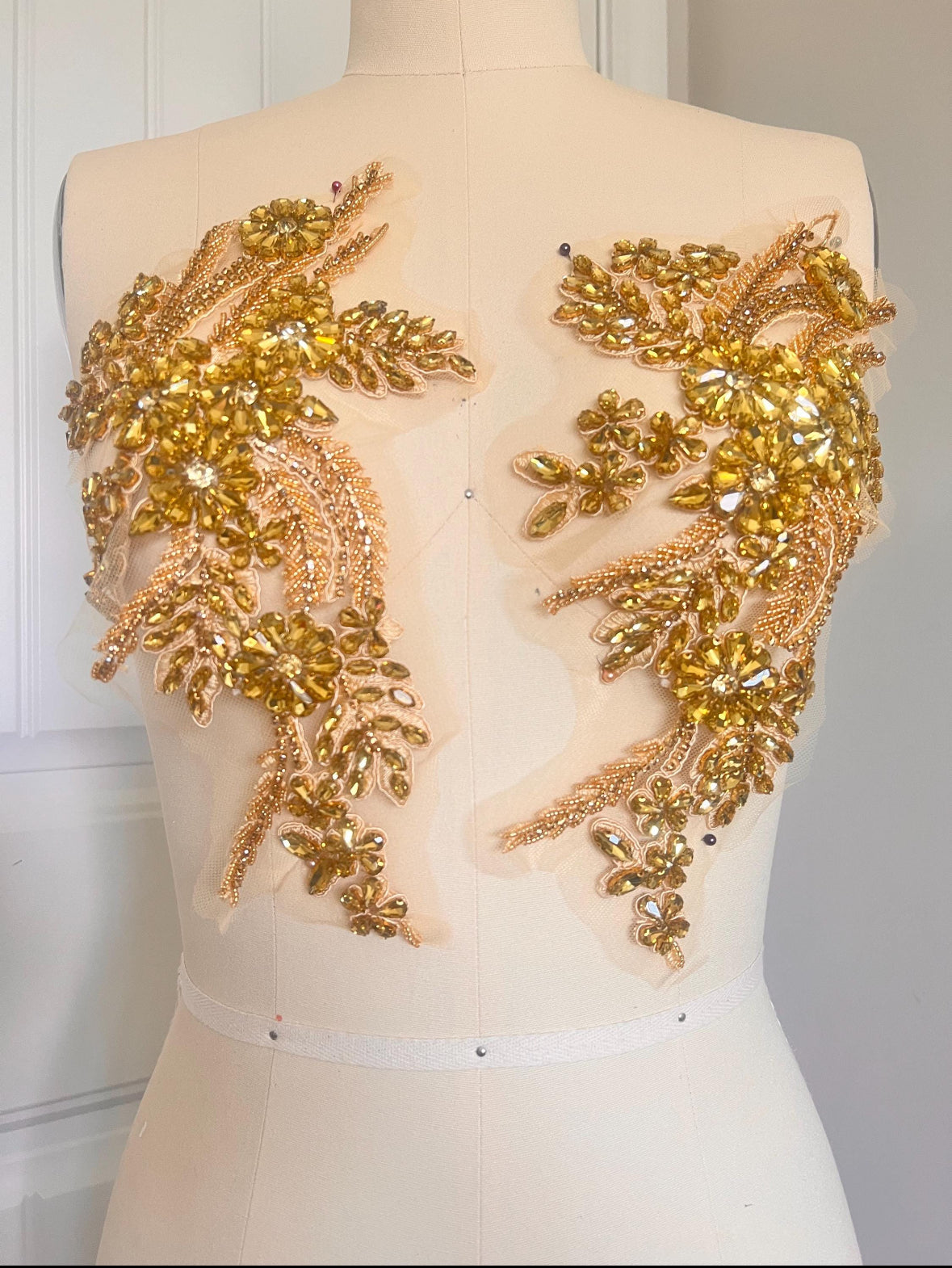 Mannequin wearing a backless dress with gold floral embellishments.