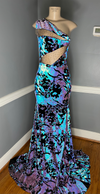 A medium-sized sequin dress featuring a mermaid train and bodice mesh cutouts, predominantly in blue, purple, and black colors by Bellz Couture in Detroit.