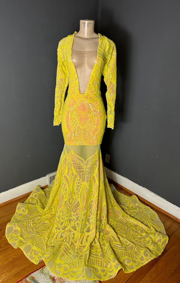 A yellow iridescent sequin v-neck gown with long sleeves and a mermaid train on a mannequin against a dark background by Bellz Couture in Detroit